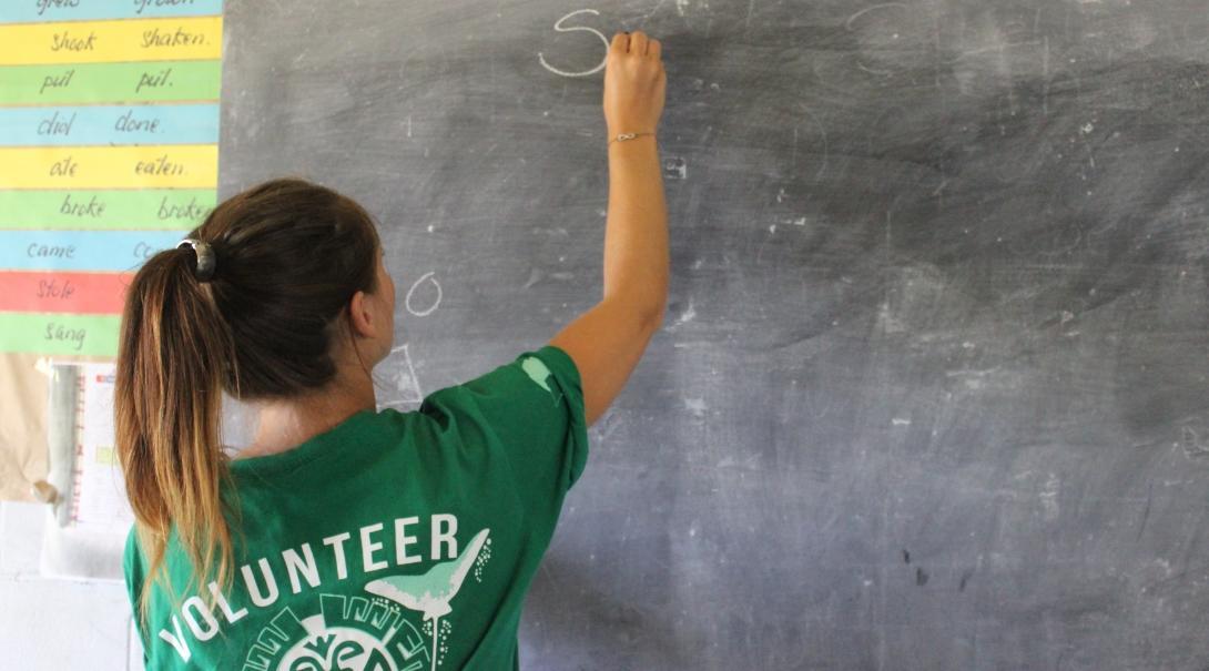 A Projects Abroad volunteer writes on a classroom board during her teaching work experience in Samoa. A volunteer teaching in Samoa writes on a classroom board.